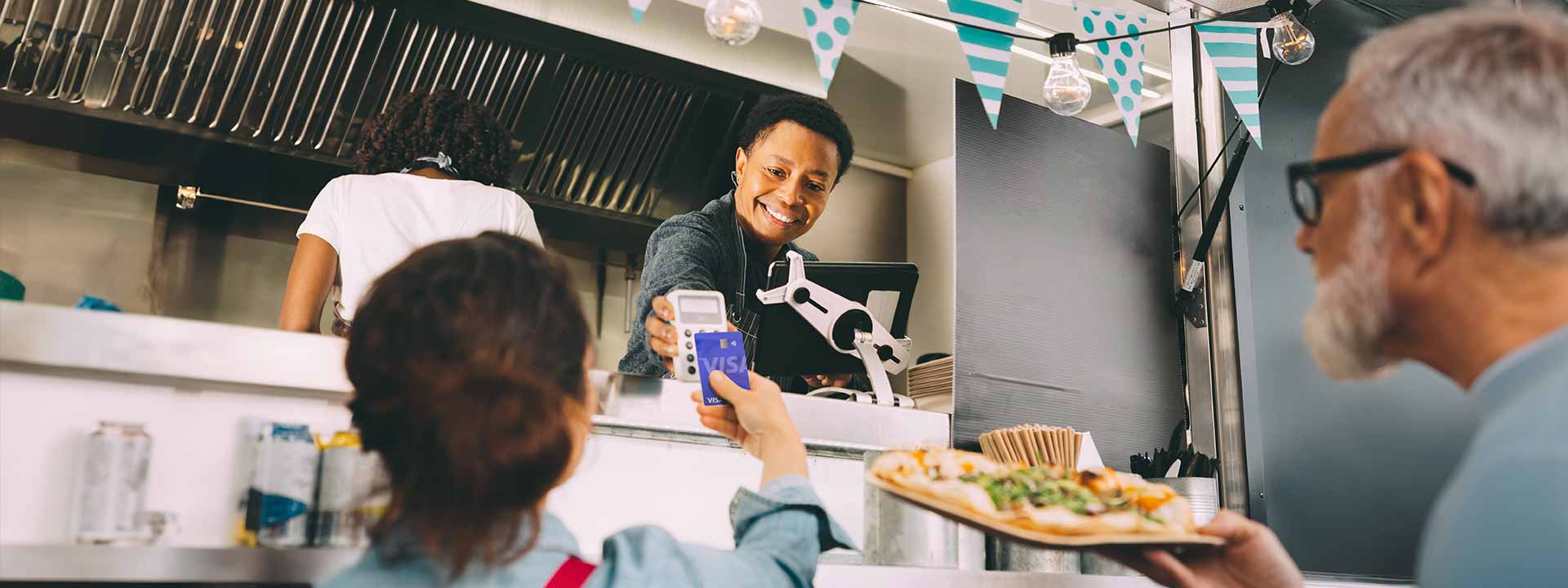 Woman purchasing food at a food truck by tapping her card at the point-of-sale system.
