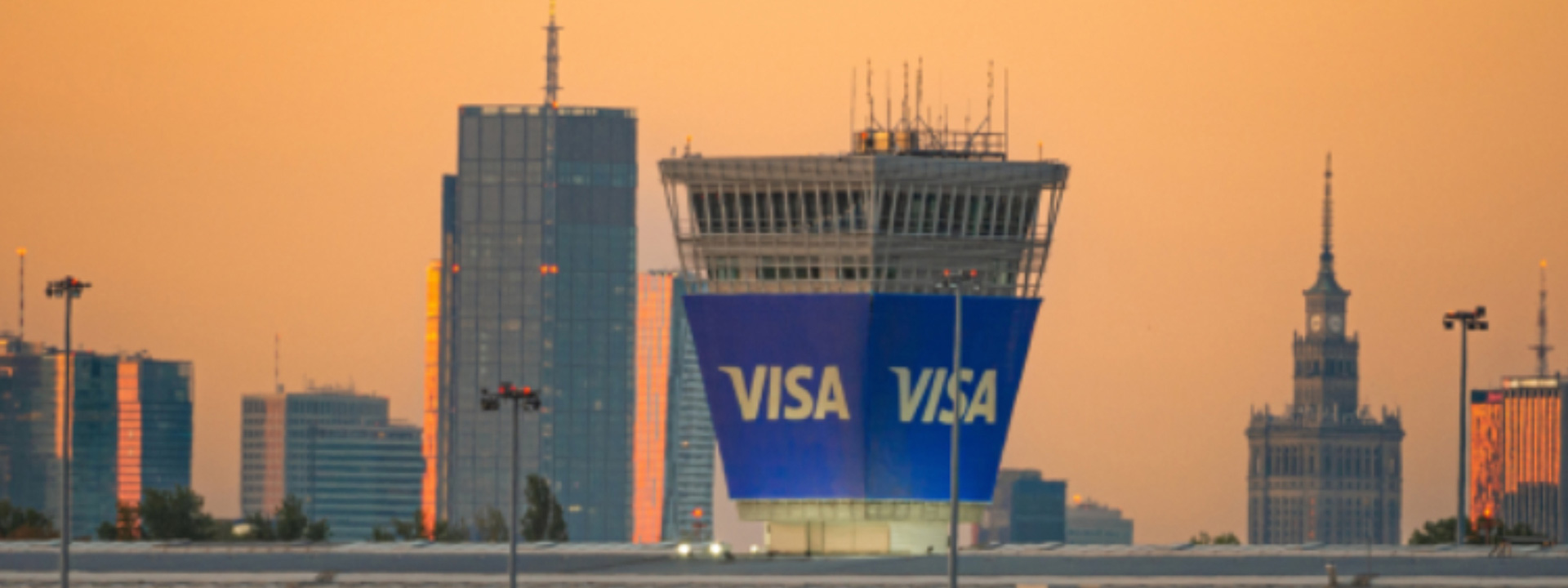 Visa signage on the new global Technology and Product Hub in Poland against the skyline at sunset.