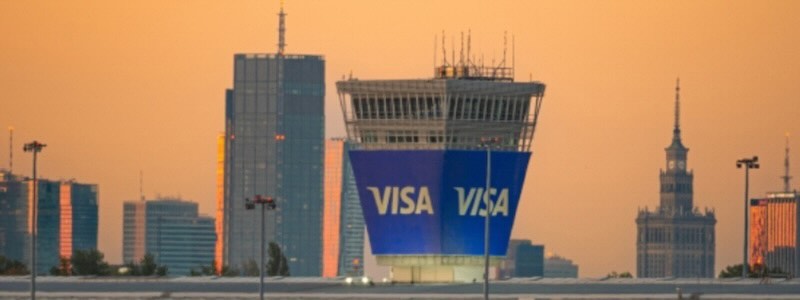 Visa signage on the new global Technology and Product Hub in Poland against the skyline at sunset.