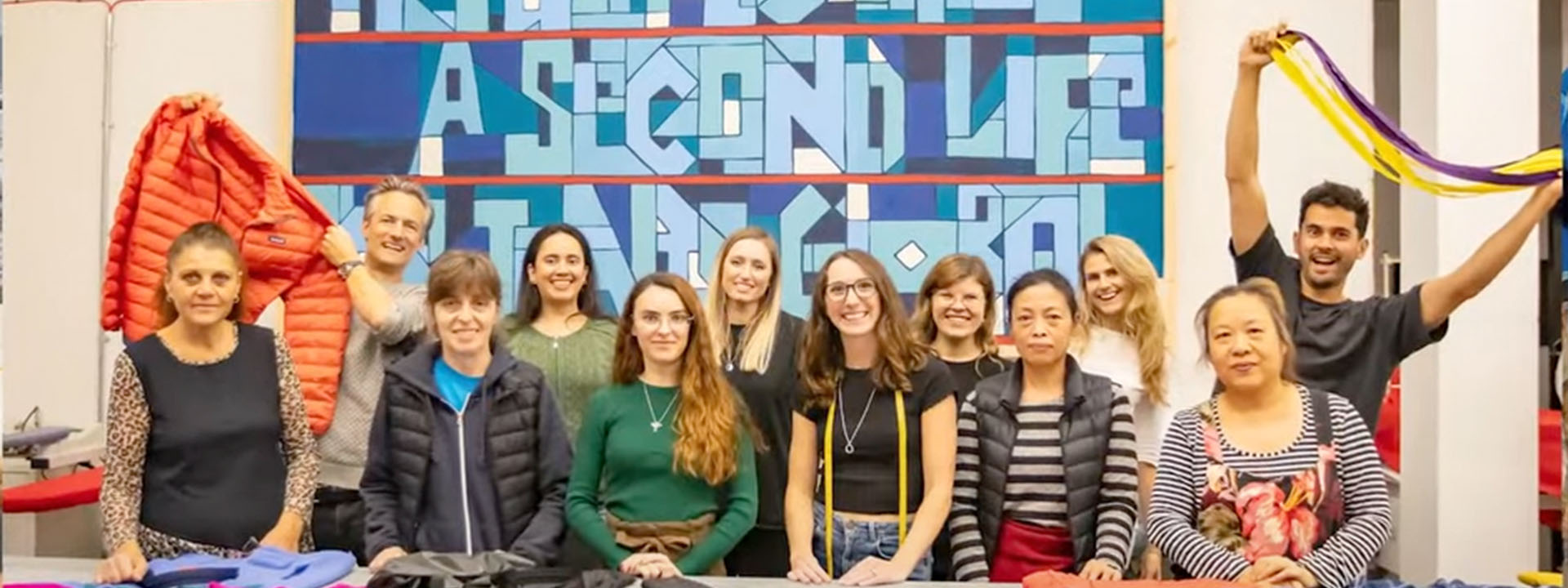 A cheerful group poses together in front of a table displaying jackets