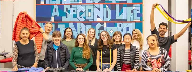 A cheerful group poses together in front of a table displaying jackets