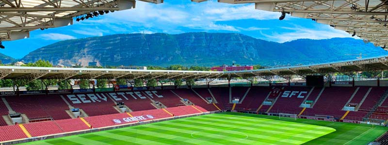 Open top football stadium with mountains in the background