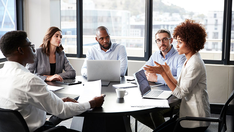 Millennial businesswoman addressing colleagues at a corporate business meeting, close up