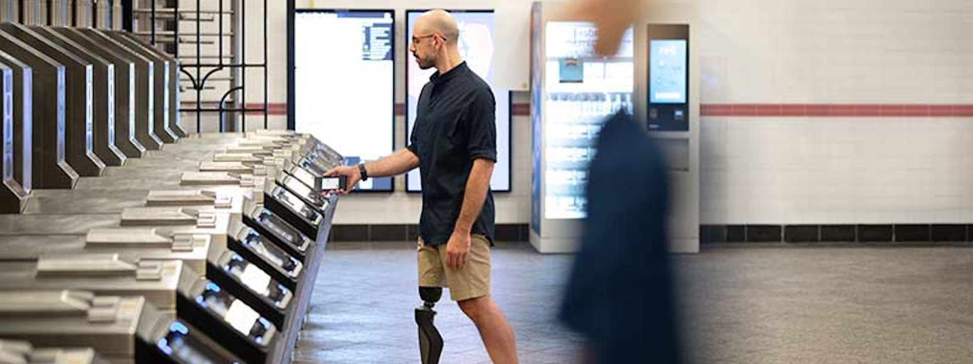 Man with a prosthetic leg taps his payment-enabled device to enter a subway station