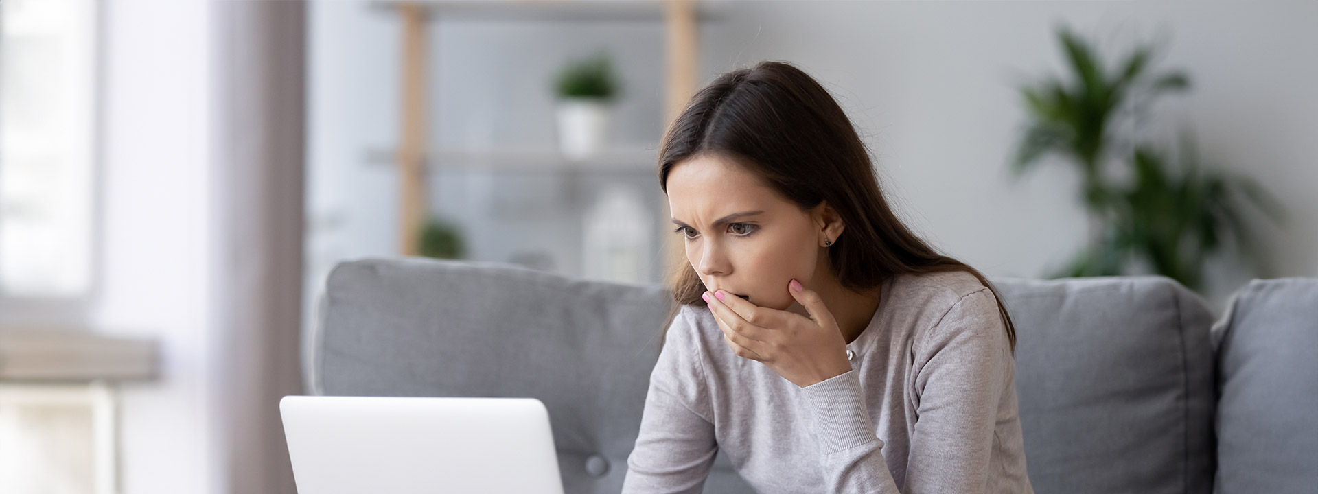 Woman looks at a laptop computer with a concerned look on her face.