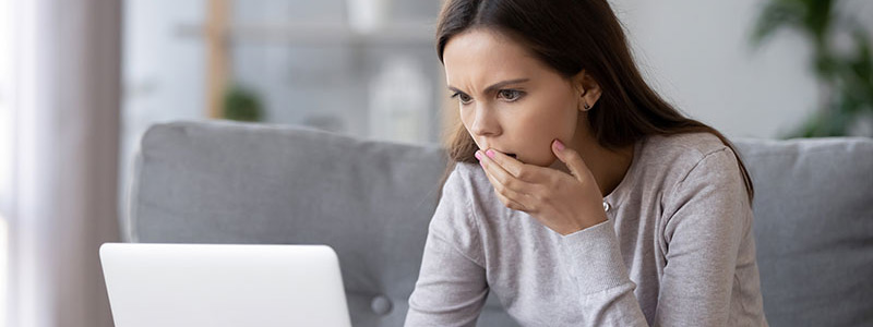 Woman looks at a laptop computer with a concerned look on her face.