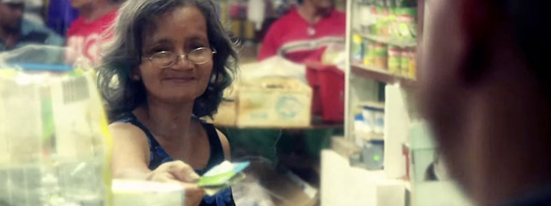 Woman behind a plexiglas divider paying with a credit card