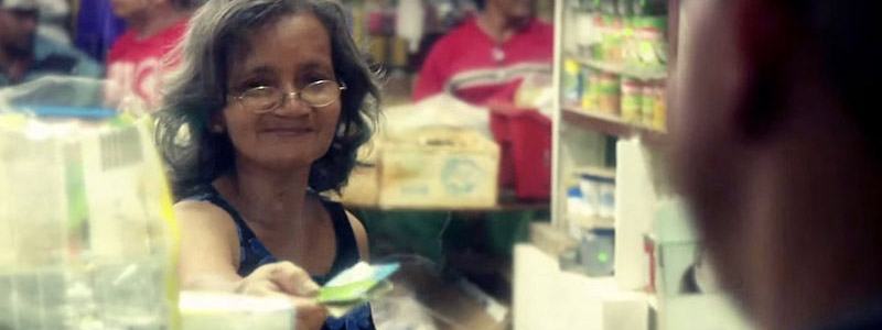 Woman behind a plexiglas divider paying with a credit card