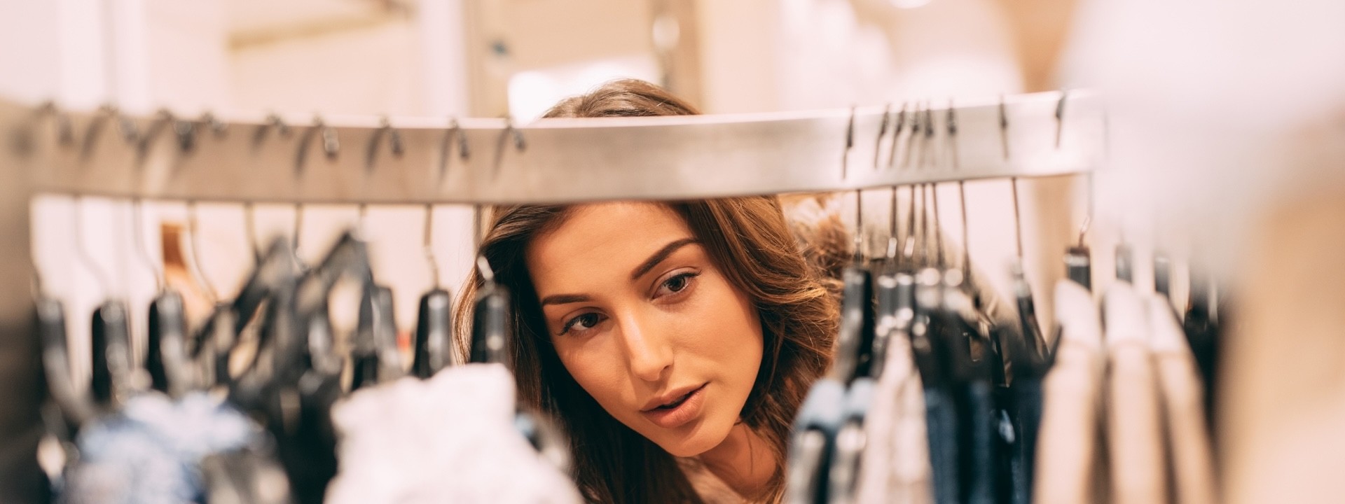 woman checking clothes on hangers at shop