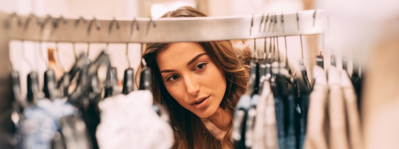 woman checking clothes on hangers at shop