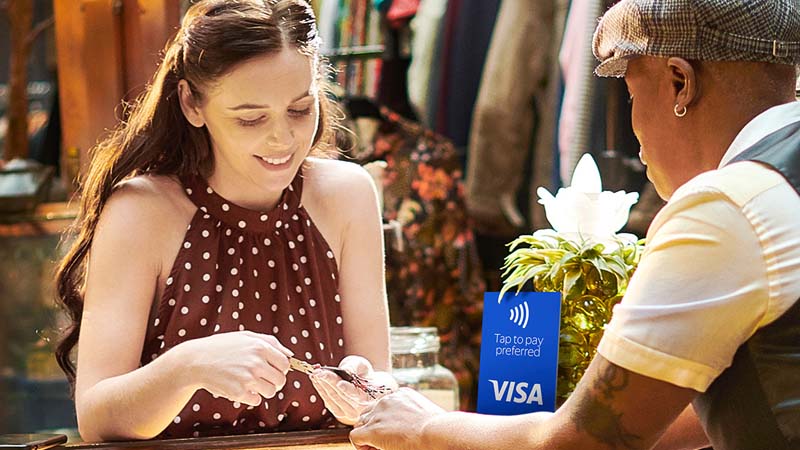 A young woman with long hair taking out her card and handing it to a merchant at a boutique.
