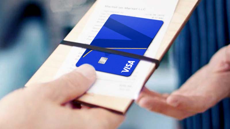 Close up of hands handing over their Visa card attached to their restaurant bill.