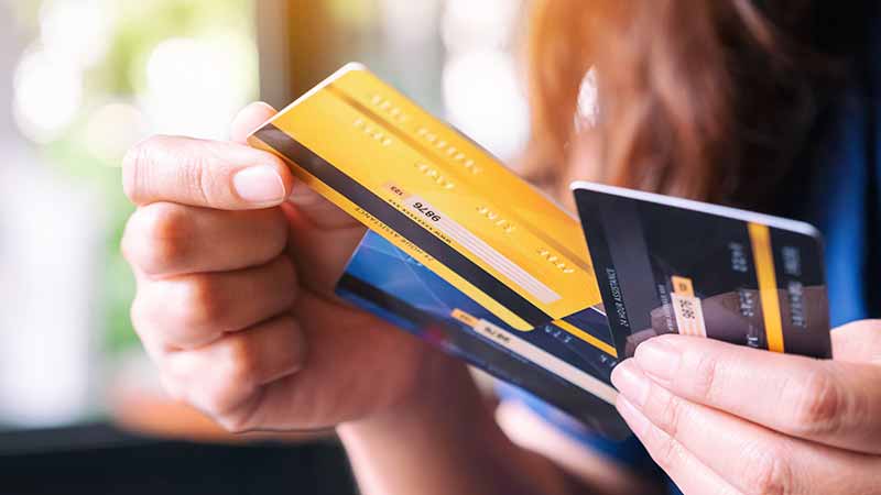 Close up of person holding three credit cards.