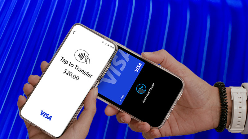 Two hands hold smartphones; one displays " Tap to Transfer $20.00" and the other a Visa card