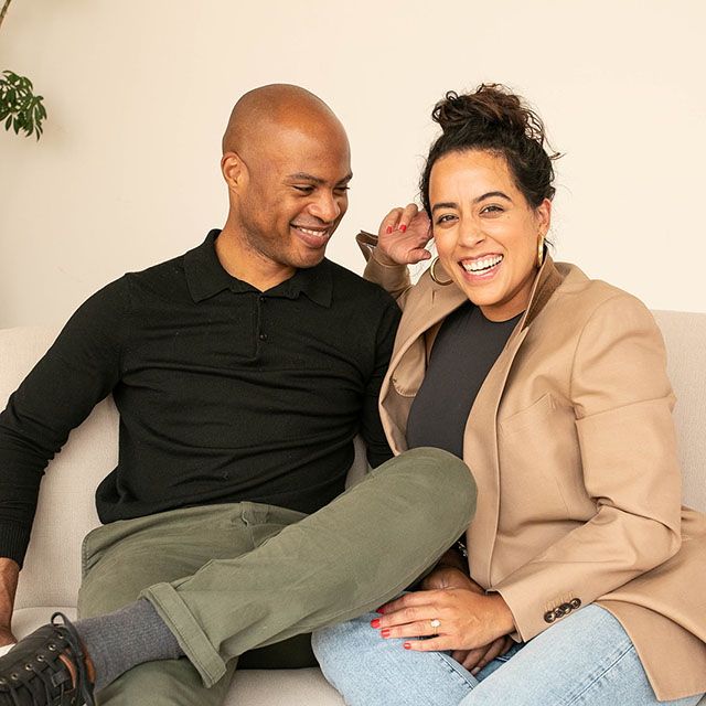 Woman and man sitting on a couch laughing together.