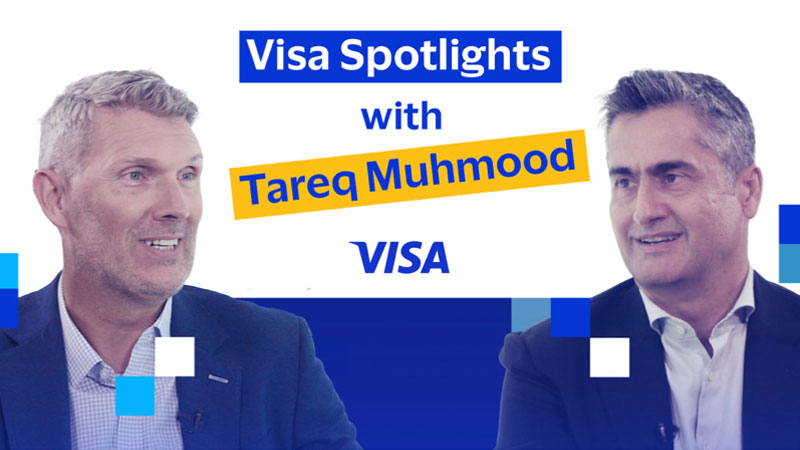 Two men in business attire sit against a blue and white geometric background. Text reads "Visa Spotlights with Tareq Muhmood." Both appear engaged and smiling.